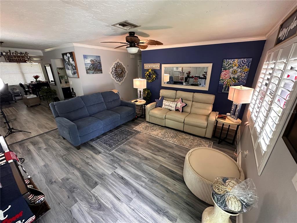 A living room features a blue sofa, a beige sofa, and wood-look flooring — 9470 JOEL DRIVE, SEMINOLE, FL