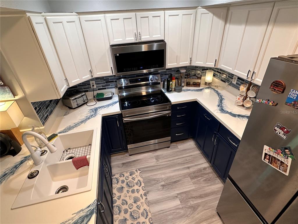 A kitchen features white upper cabinets, dark blue lower cabinets, and white countertops with blue accents — 9470 JOEL DRIVE, SEMINOLE, FL