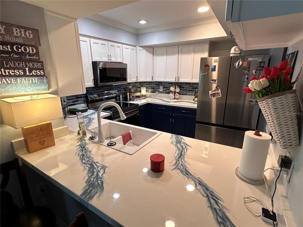 A kitchen features white upper cabinets, dark lower cabinets, and white countertops with blue veining — 9470 JOEL DRIVE, SEMINOLE, FL