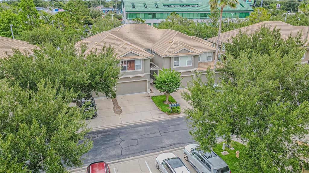 An aerial view shows a multi-unit residential building with a tan tile roof and garages — 3331 COVERED BRIDGE DRIVE E, DUNEDIN, FL
