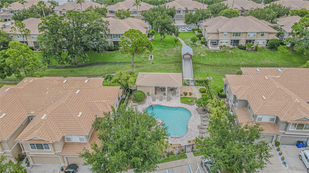 An aerial view of a residential community featuring a swimming pool, clubhouse, and pedestrian bridge — 3331 COVERED BRIDGE DRIVE E, DUNEDIN, FL