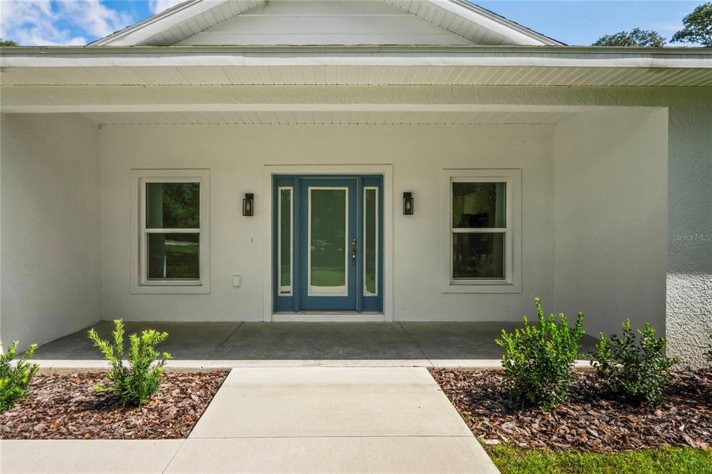A front porch features a blue door with sidelights and two windows on a white house — 279 W PEARSON STREET, HERNANDO, FL