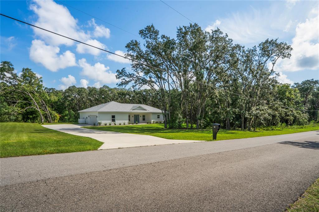 A white single-story house with a concrete driveway sits on a grassy lot with trees — 279 W PEARSON STREET, HERNANDO, FL