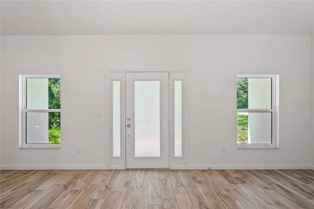 A bright room with wood-look tile flooring, a central front door, and two side windows — 279 W PEARSON STREET, HERNANDO, FL