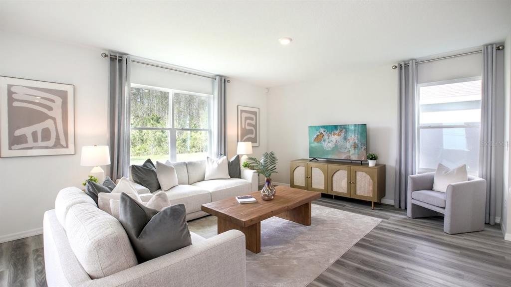 A bright living room features a light-colored sofa, wooden coffee table, and a television console — 35477 KINSEY POINT, ZEPHYRHILLS, FL