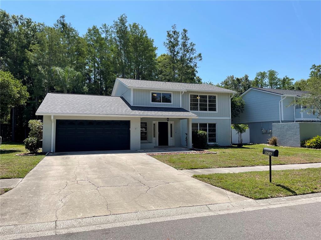 A two-story house with a gray exterior, a dark garage door, and a concrete driveway — 4406 GRAINARY AVENUE, TAMPA, FL