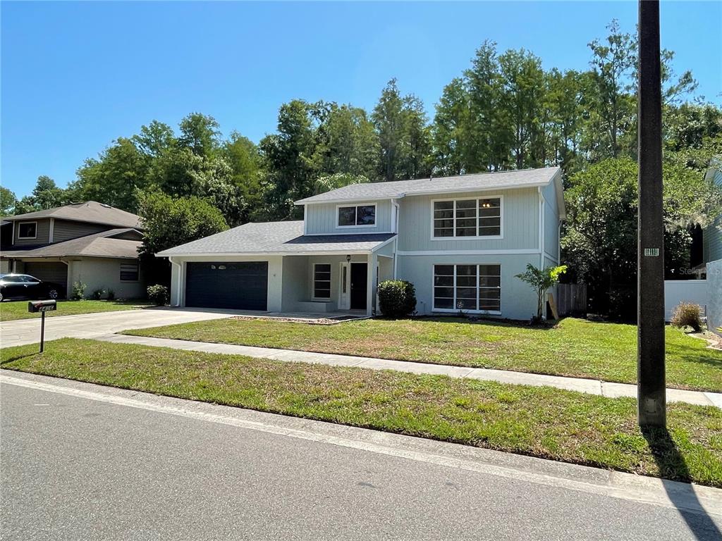 A two-story house with light gray siding, a dark garage door, and a front lawn — 4406 GRAINARY AVENUE, TAMPA, FL