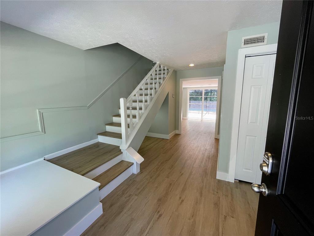 An entryway features light wood flooring, a white staircase with lattice railings, and a closet — 4406 GRAINARY AVENUE, TAMPA, FL