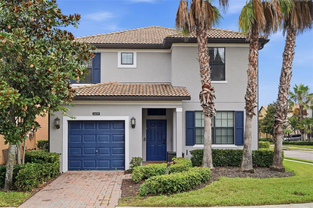 A two-story house with a blue garage door, blue front door, and palm trees — 5439 SOLTERRA CIRCLE, DAVENPORT, FL