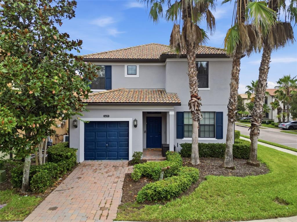 A two-story house with a blue garage door, blue front door, and palm trees outside — 5439 SOLTERRA CIRCLE, DAVENPORT, FL