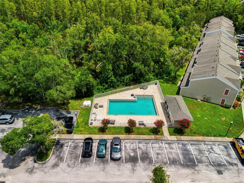 An aerial view shows a community swimming pool surrounded by a fence, parking, and trees — 5416 CARROLLWOOD KEY DRIVE UNIT 8, TAMPA, FL