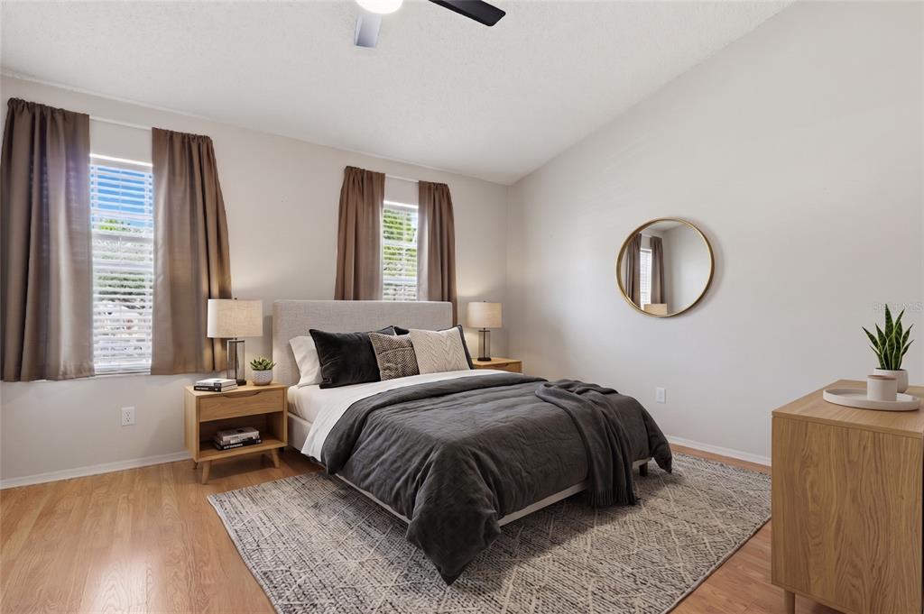 A bedroom features a bed with dark bedding, two nightstands, and a round wall mirror — 5416 CARROLLWOOD KEY DRIVE UNIT 8, TAMPA, FL
