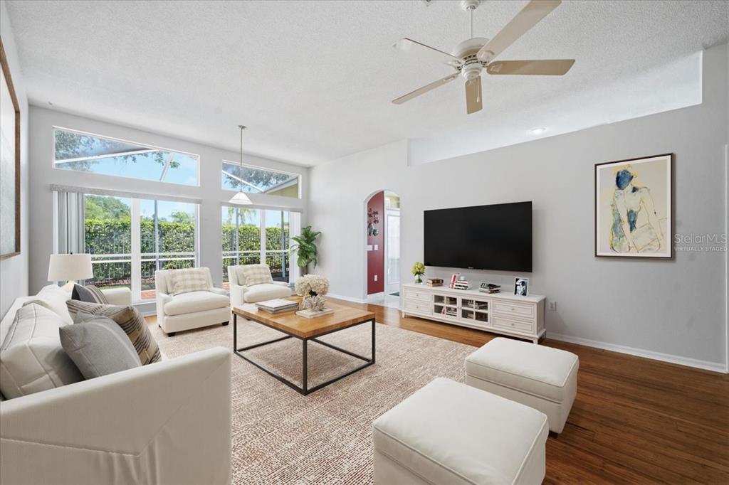 A screened-in patio with brick flooring sits beside a grassy yard and metal fence — 4628 CORSAGE DRIVE, LUTZ, FL
