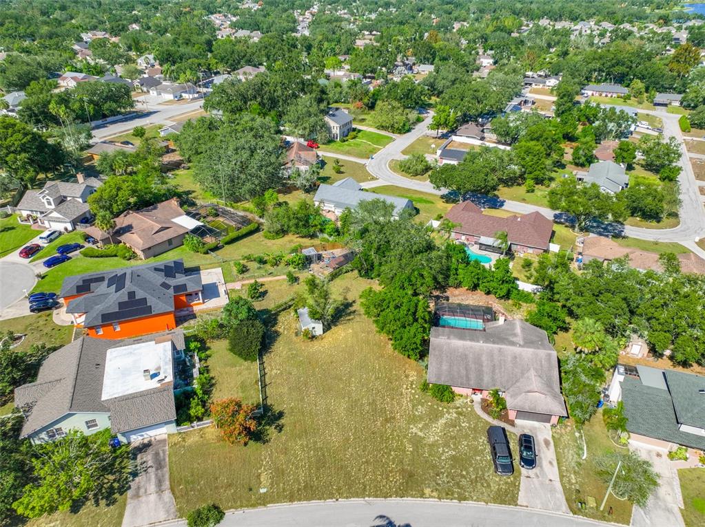 An aerial view shows a vacant lot situated between two suburban houses with swimming pools — 1114 CLASSIC DRIVE, VALRICO, FL