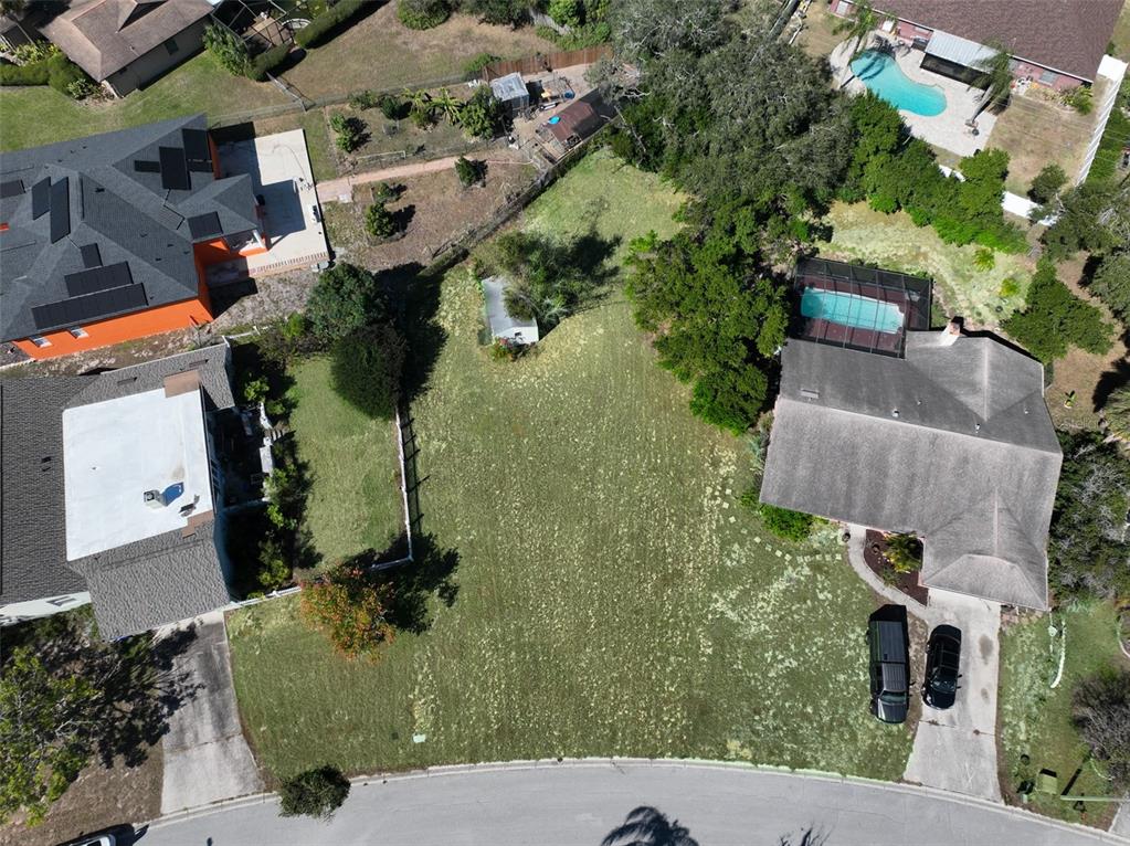 An aerial view shows a vacant residential lot situated between two houses with swimming pools — 1114 CLASSIC DRIVE, VALRICO, FL
