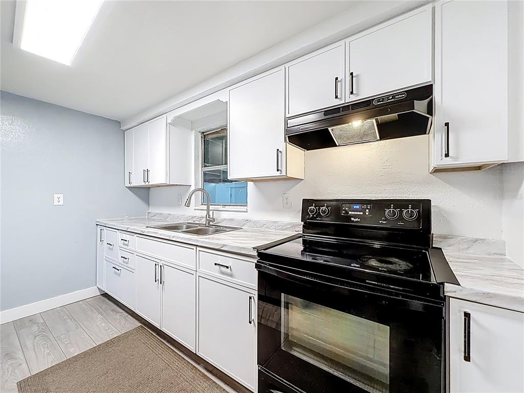 A dining area with a wooden table and chairs adjacent to a kitchen and living room — 544 MERCURY AVENUE, ORLANDO, FL
