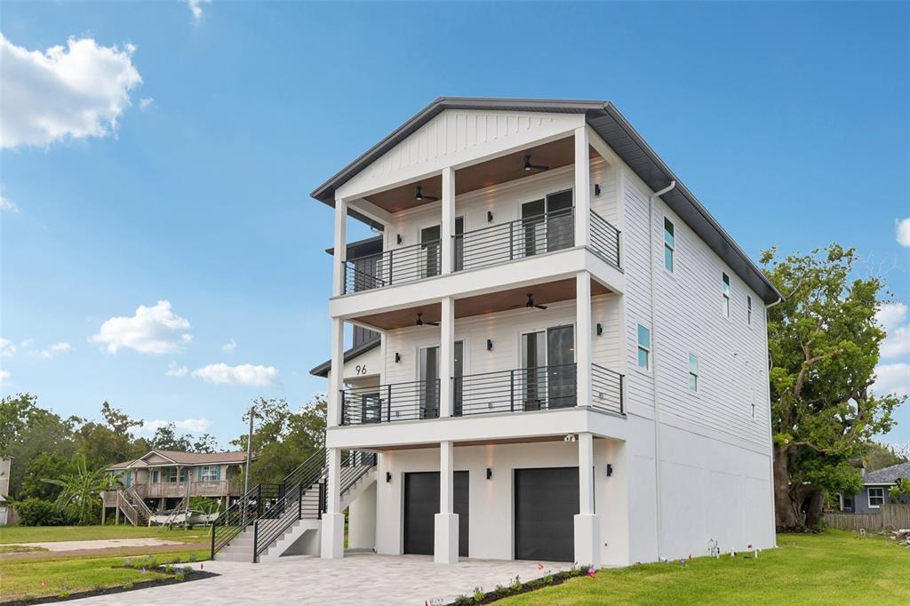 An aerial view shows a coastal neighborhood with houses, palm trees, and a long causeway — 96 SHORE DRIVE, TARPON SPRINGS, FL
