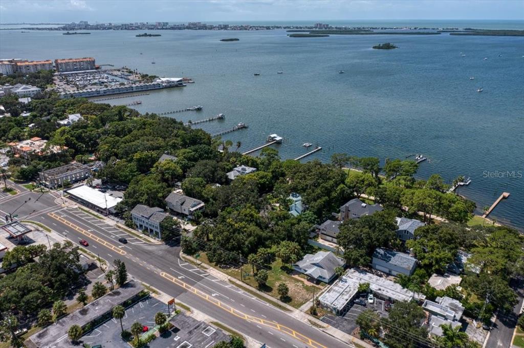 An aerial view shows a coastal neighborhood with houses, trees, and docks along the water — 1040 BROADWAY, DUNEDIN, FL