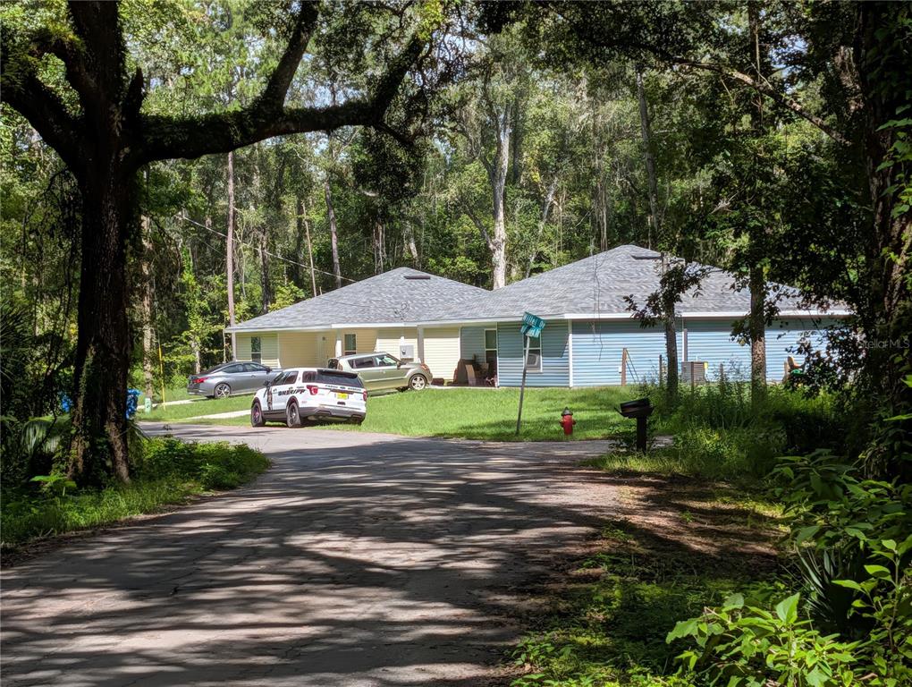 A sheriff's vehicle and two cars are parked in front of a light-colored residential house — 0 WILDWOOD DRIVE, BROOKSVILLE, FL