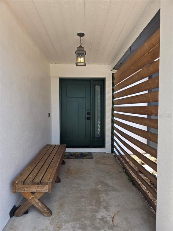 A covered entryway features a wooden bench, a dark green door, and a slatted privacy screen — 7005 TALBOT DR, ORLANDO, FL