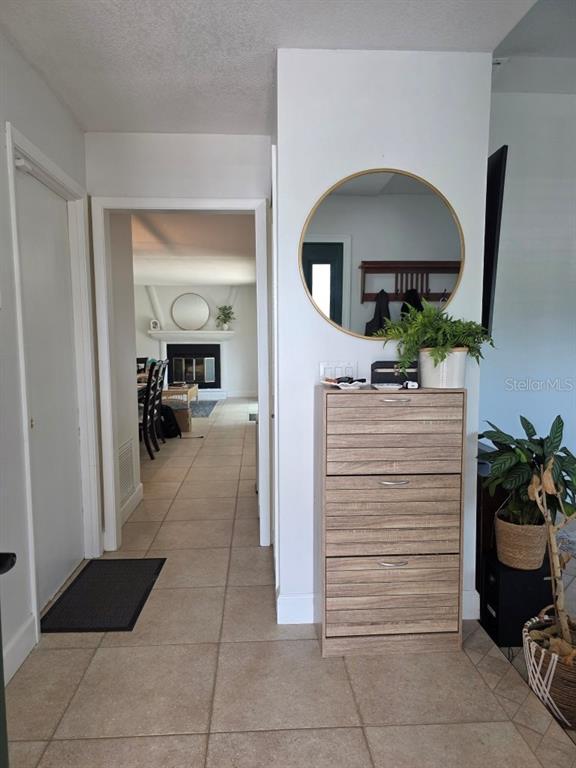 A tiled entryway features a wooden shoe cabinet, a round wall mirror, and a doorway — 7005 TALBOT DR, ORLANDO, FL