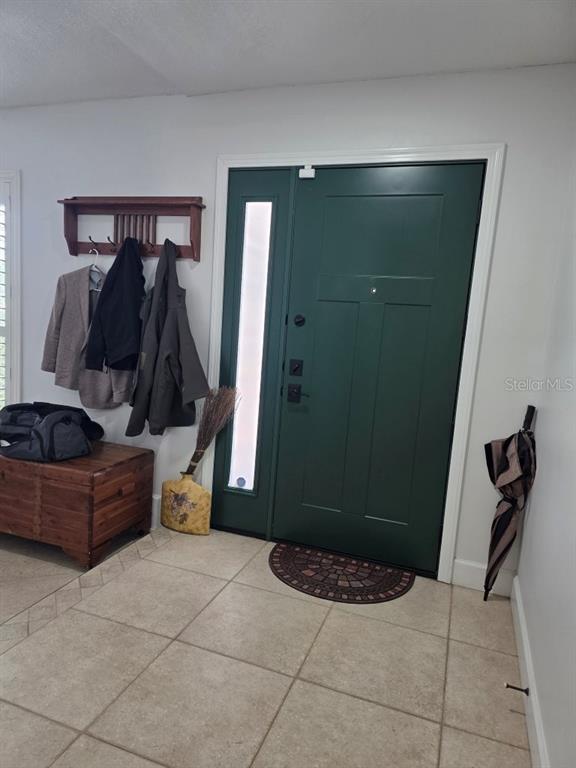 An entryway features a dark green front door, a wooden coat rack, and tiled flooring — 7005 TALBOT DR, ORLANDO, FL