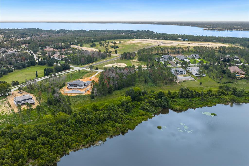 An aerial view shows houses under construction near a lake and a large body of water — 16409 PENDIO DRIVE, MONTVERDE, FL