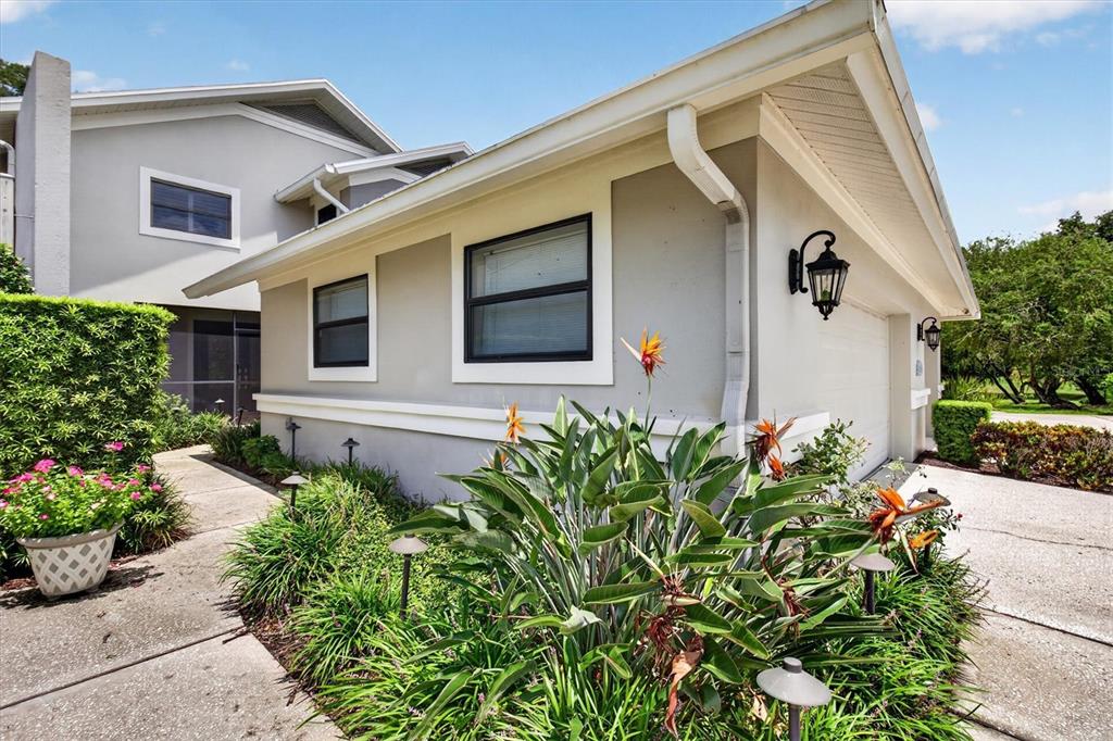 A gray multi-unit residential building with attached garages and a blooming crape myrtle tree — 2631 ROYAL LIVERPOOL DRIVE, TARPON SPRINGS, FL