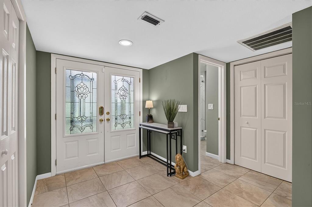 An entryway features double glass-paneled doors, tiled flooring, a console table, and sage green walls — 2631 ROYAL LIVERPOOL DRIVE, TARPON SPRINGS, FL
