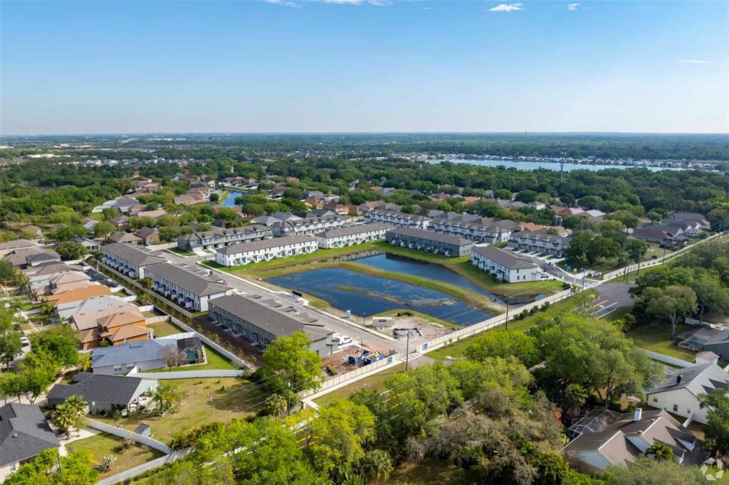 An aerial view shows a residential neighborhood with townhomes surrounding a central retention pond — 8683 HOLLY GROVE COURT UNIT Oakville, RIVERVIEW, FL
