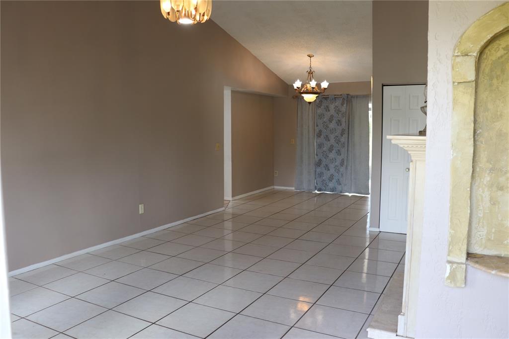 A room with light-colored tile flooring, beige walls, and two hanging chandeliers — 11012 BRIGHTSIDE DRIVE, TAMPA, FL