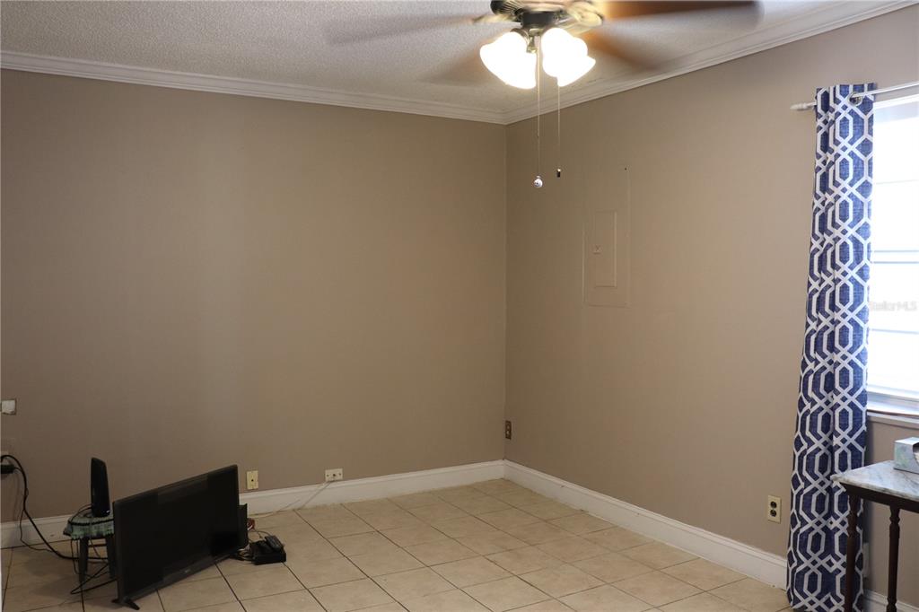 An empty room with beige walls, tile flooring, a ceiling fan, and a patterned curtain — 11012 BRIGHTSIDE DRIVE, TAMPA, FL