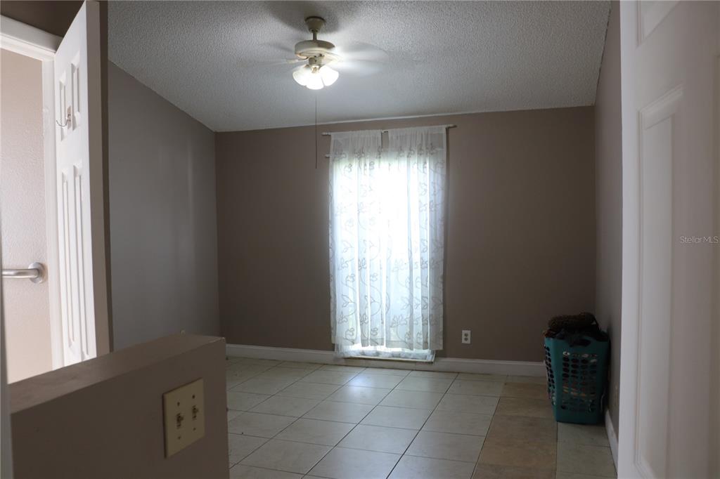 A room with light-colored tile flooring, beige walls, a ceiling fan, and a window — 11012 BRIGHTSIDE DRIVE, TAMPA, FL