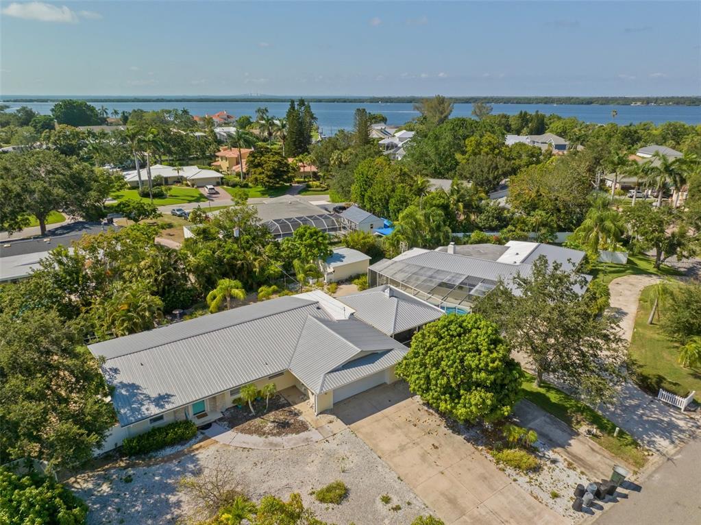 An aerial view shows a single-story house with a metal roof and a pool enclosure — 7202 18TH AVENUE NW, BRADENTON, FL