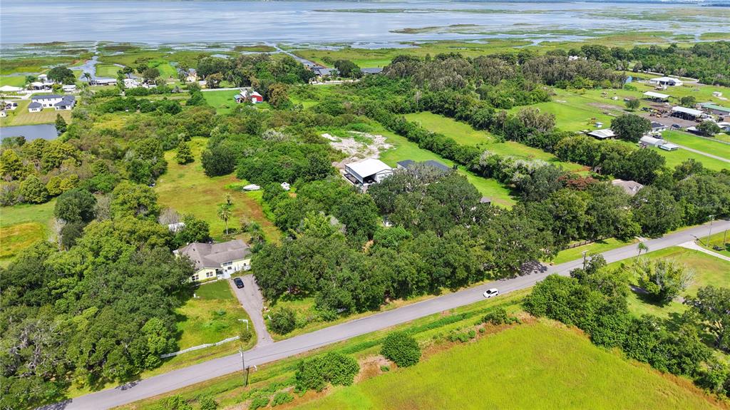 An aerial view shows a house, a large workshop, and trees along a rural road — 3120 CHEROKEE ROAD, ST CLOUD, FL