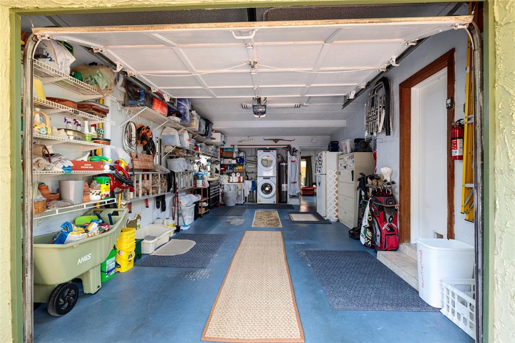 A garage with blue painted floors, storage shelving, a laundry unit, and a golf bag — 505 SANDY HOOK ROAD UNIT 505, TREASURE ISLAND, FL