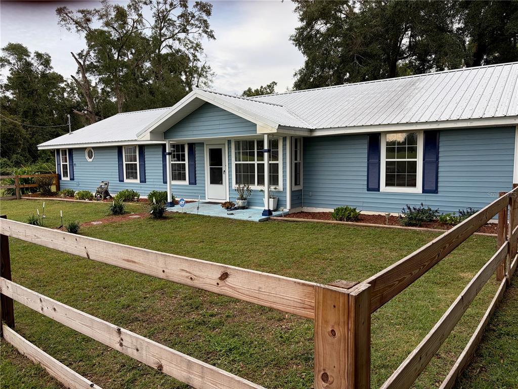 A blue single-story house with a metal roof and a stone path in the yard — 1890 NW 167TH PLACE, TRENTON, FL