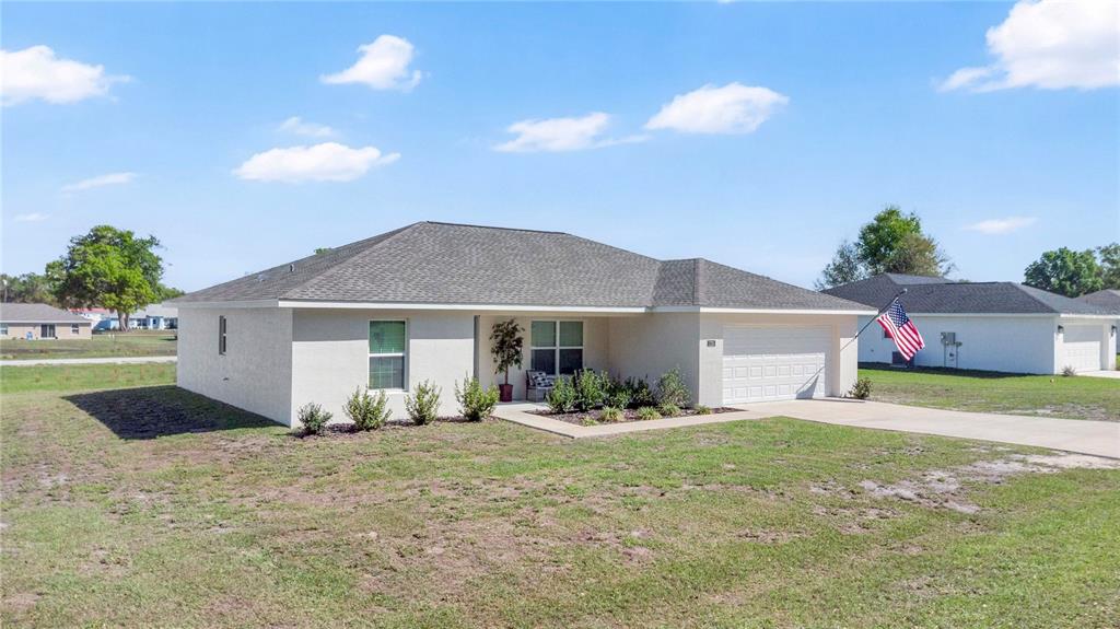A single-story stucco house with a gray shingled roof and a two-car garage — 1725 NE 160TH PLACE, CITRA, FL