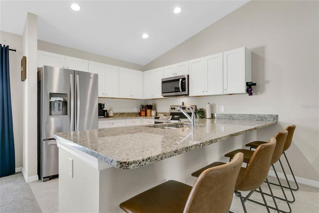 A kitchen with white cabinets and stainless steel appliances opens to a dining area — 1725 NE 160TH PLACE, CITRA, FL