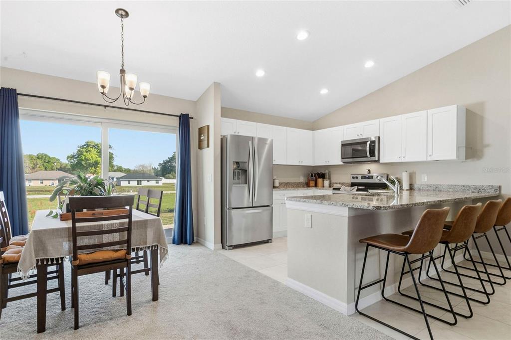 A kitchen features white cabinets, granite countertops, stainless steel appliances, and a breakfast bar — 1725 NE 160TH PLACE, CITRA, FL