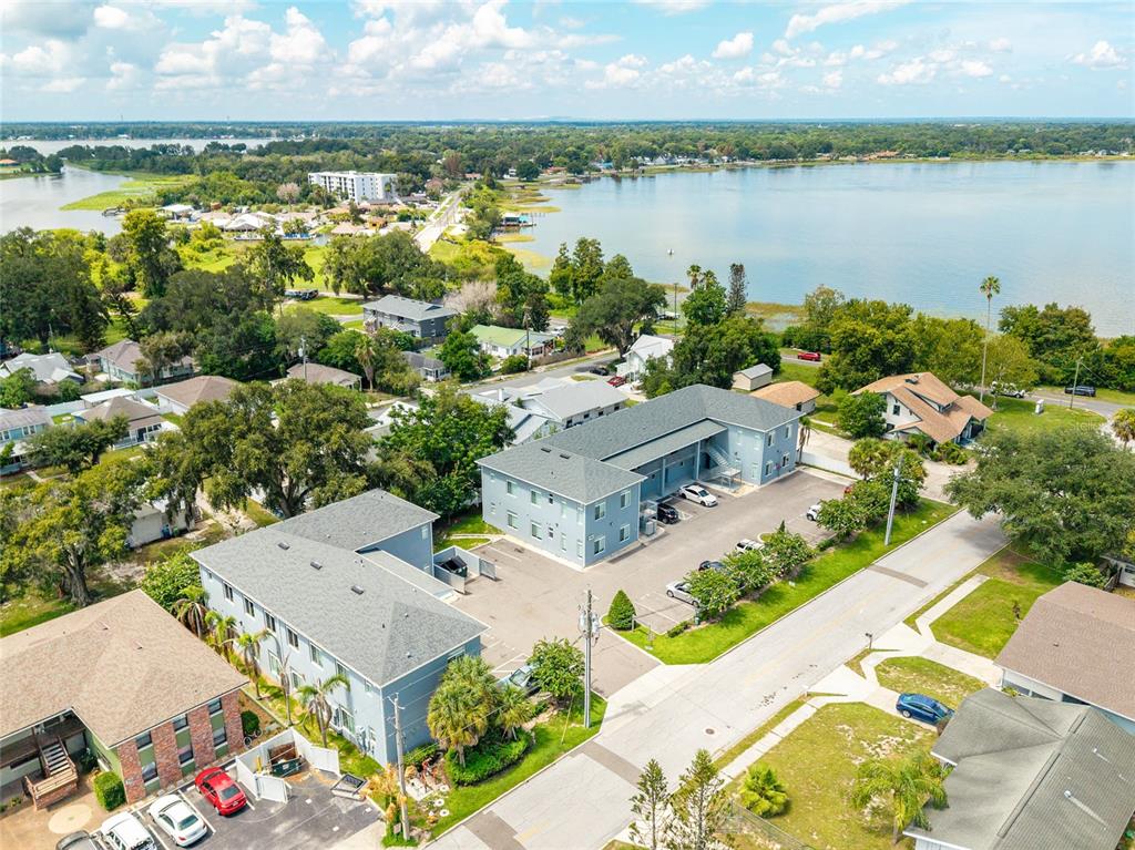 An aerial view shows two multi-story apartment buildings with parking lots near a large lake — 750 AVE C SW, WINTER HAVEN, FL