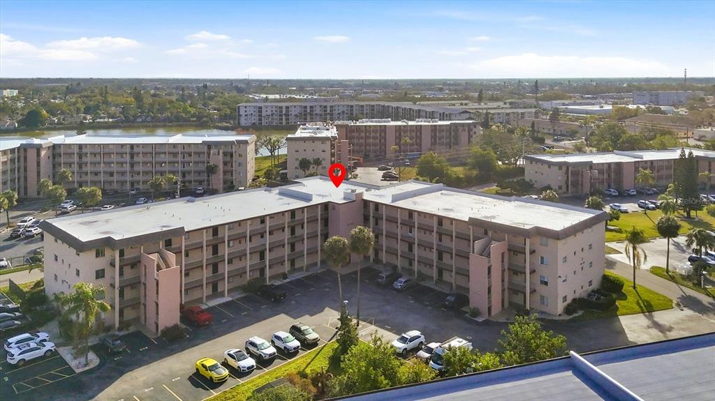 An aerial view shows a multi-story apartment complex with a parking lot and palm trees — 4143 HERON WAY 207 BLDG E, BRADENTON, FL