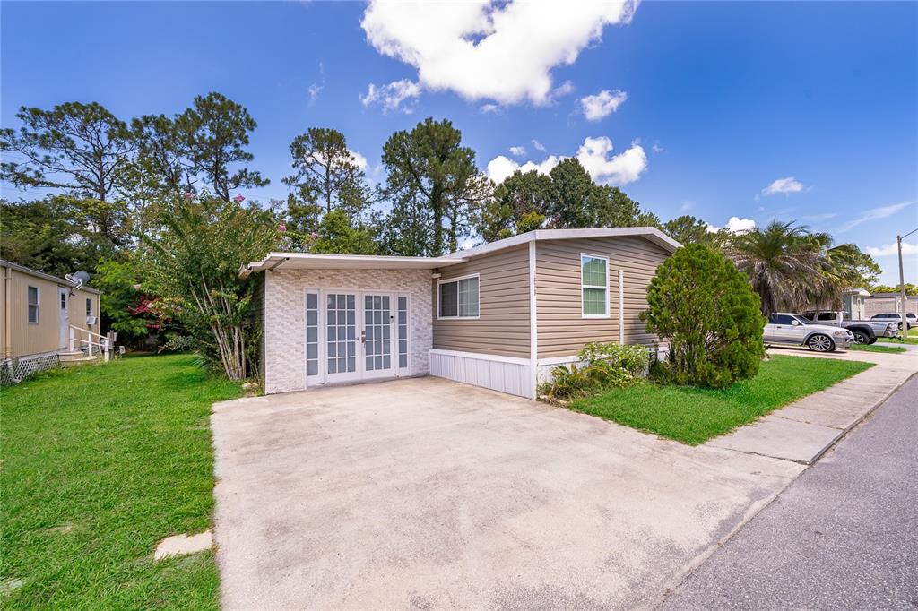 A single-story mobile home with tan siding, a concrete driveway, and a white-framed glass door — 1838 ANNAPOLIS AVENUE, ORLANDO, FL