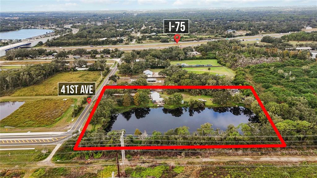 An aerial view shows a rectangular property containing a pond and house near a highway — 8011 41ST AVENUE E, BRADENTON, FL