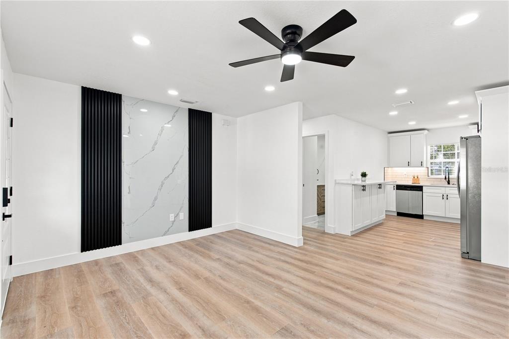 A living area with a marble-look accent wall, black slats, and an adjacent white kitchen — 3619 N 72ND STREET, TAMPA, FL