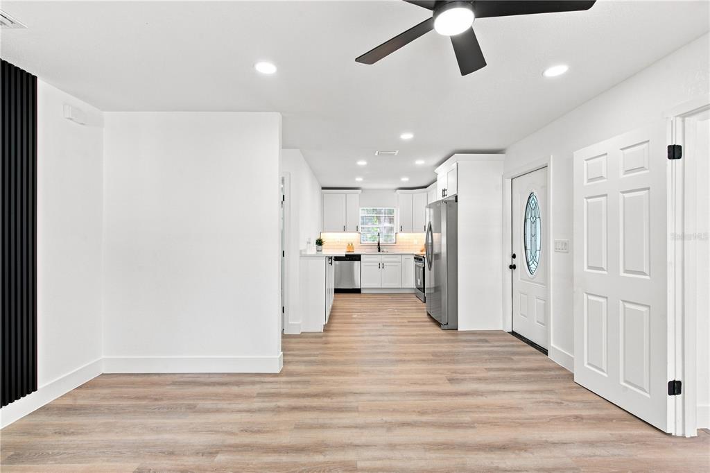A bright kitchen with white cabinets and stainless steel appliances opens into a living area — 3619 N 72ND STREET, TAMPA, FL