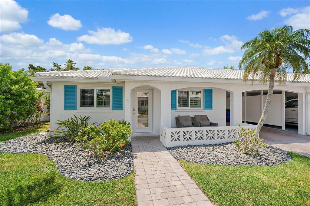 A white single-story house with blue shutters, a paved walkway, and a small front porch — 706 SPANISH DRIVE S, LONGBOAT KEY, FL