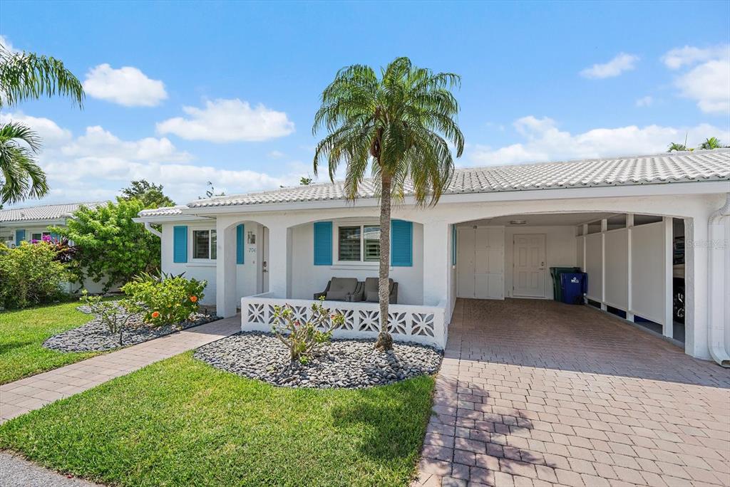 A single-story white house features a palm tree, a paved driveway, and a covered porch — 706 SPANISH DRIVE S, LONGBOAT KEY, FL