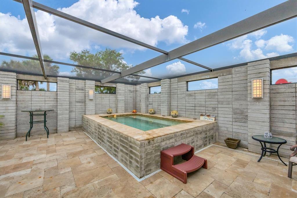 An elevated rectangular pool sits on a stone patio inside a screened-in concrete block enclosure — 45 CAPE HAZE DRIVE, PLACIDA, FL