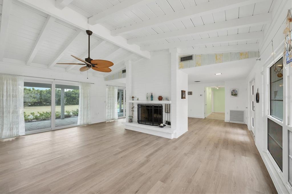 A bright living room features a white vaulted ceiling, wood flooring, and a central fireplace — 45 CAPE HAZE DRIVE, PLACIDA, FL
